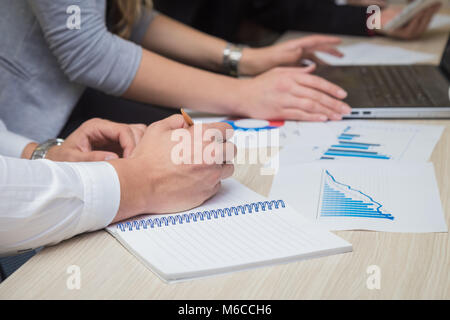Close up of man hands taking notes and business documents and charts on the table during the business meeting Stock Photo