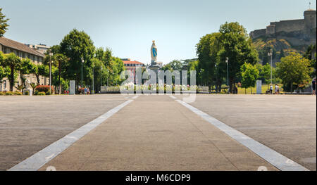 Lourdes, France - June 22, 2017 : view of the esplanade in front of the basilica of Lourdes with a statue of the Virgin Mary crowned on a summer day Stock Photo