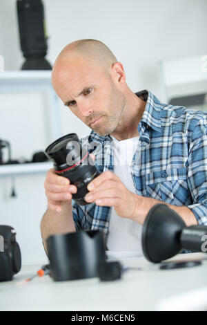 focused man fixing camera at his workplace Stock Photo