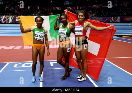 Ivory Coast's gold winner Murielle Ahoure (centre), Ivory Coast's silver winner Marie-Josee Ta Lou (left) and Switzerland's bronze winner Mujinga Kambundji (right) celebrate after the Women's 60m final during day two of the 2018 IAAF Indoor World Championships at The Arena Birmingham. Stock Photo