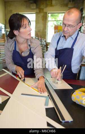 two carpenters are talking while holding papers and ruler Stock Photo