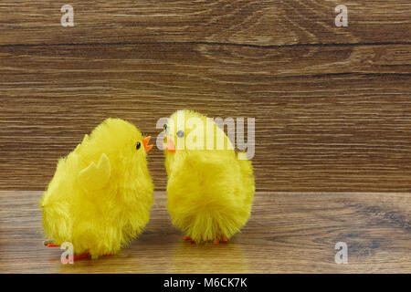 Two yellow chickens on a wooden background as interesting Easter decoration.Horizontal view. Stock Photo