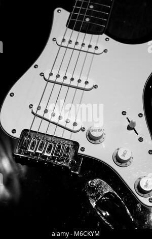 front part of the body of a white electric guitar on black background ...