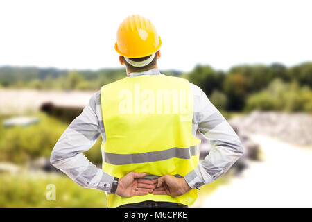Injured construction worker or engineer suffering backpain in lower back area outdoor at work Stock Photo