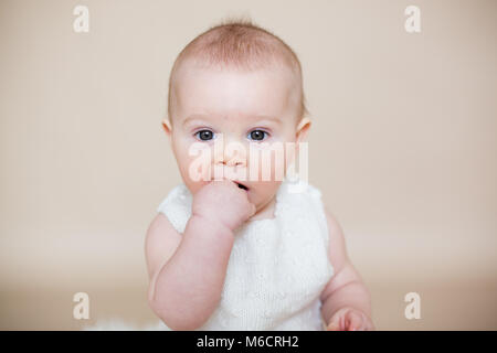 Close portrait of cute little baby boy, isolated on beige background, baby making different facial expressions, crying, sad, smiling, laughing Stock Photo