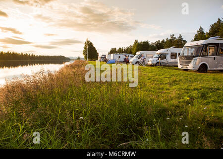 Motorhomes at a Campsite in Sweden, parked with a view over the river. The river is Angermanalven and the campsite is in the village of Asele. Stock Photo