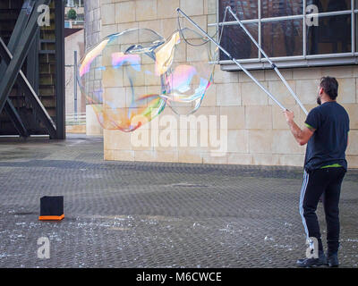Lonely street performer blows giant bubbles. Stock Photo