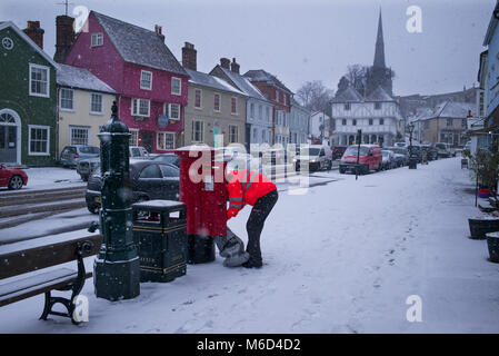 Thaxted Essex England UK. Postman collects mail from post box in Town Street Thaxted as snow continues to fall. 2 March 2018 Stock Photo