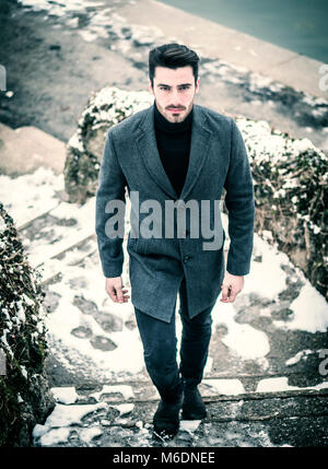 Handsome young man in snowy park Stock Photo