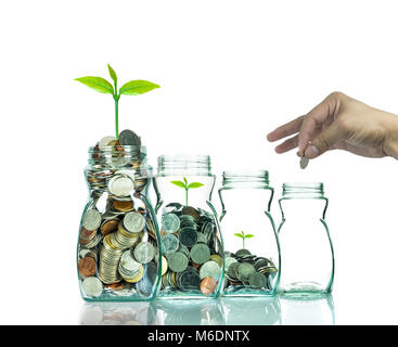 Hand putting mix coins and seed in clear bottle on white background,Business investment growth concept Stock Photo