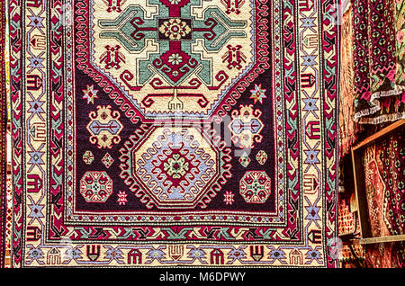 Woolen carpet with geometric ethnic patterns with red stylized curls  on a brown with white background in centered,at Sunday fair clearance sale of so Stock Photo