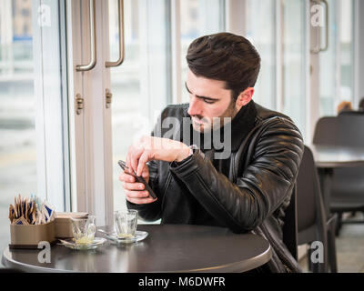 Young Man Drinking Coffee While Looking at Phone Stock Photo