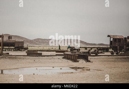 Two young children play on their playground of rusty ruins of an old abandoned train in Bolivia Stock Photo