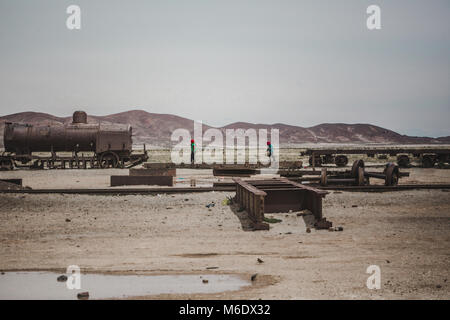 Two young children play on their playground of rusty ruins of an old abandoned train in Bolivia Stock Photo