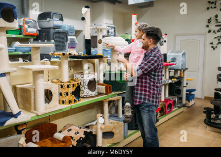Father and little daughter buying supplies for cat in petshop. Family chooses accessories for cat in pet shop Stock Photo