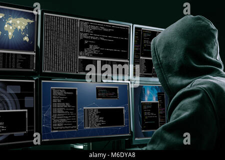 Rear View Of A Hacker Using Multiple Computers For Stealing Data In Office Stock Photo