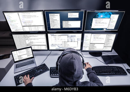 High Angle View Of A Hacker Stealing Information From Multiple Computers In Office Stock Photo