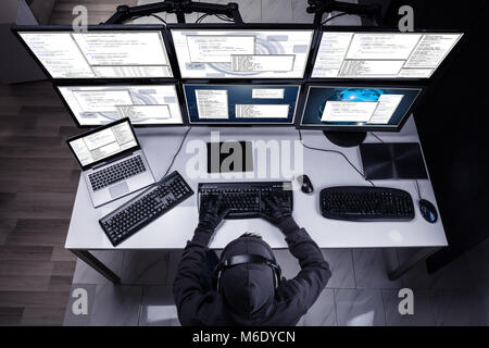 High Angle View Of A Hacker Stealing Information From Multiple Computers In Office Stock Photo