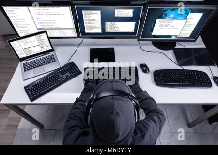 High Angle View Of A Hacker Stealing Information From Multiple Computers In Office Stock Photo