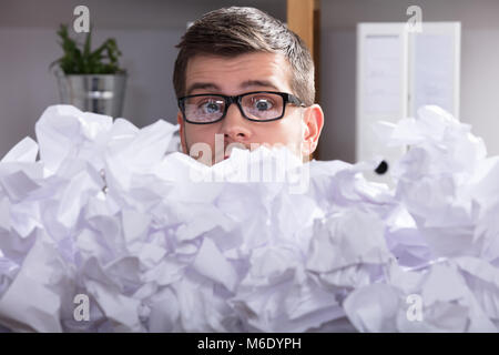 Close-up Of A Businessman Wearing Spectacles Looking At Heap Of Crumpled Paper Stock Photo