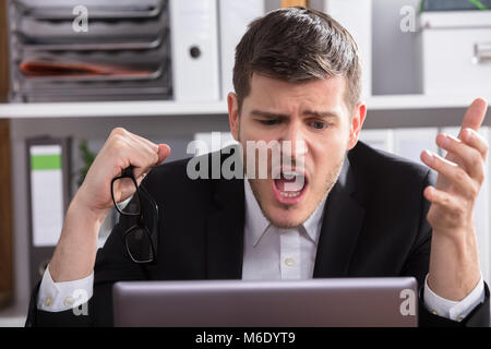 Close-up Of A Shocked Young Businessman Looking At Laptop Stock Photo