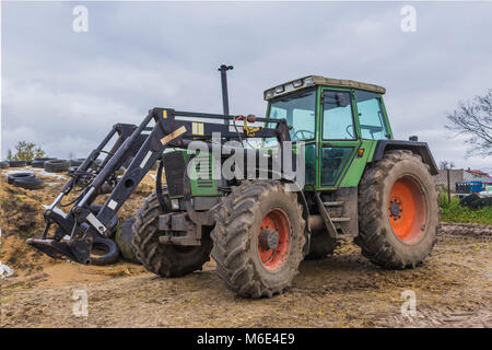 A powerful tractor designed for various jobs on an agricultural farm. Closed cabin, red wheels. Late autumn. Podlasie, Poland. Stock Photo