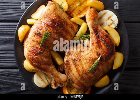 grilled chicken leg with oranges, onions and potatoes macro on a plate. Horizontal top view from above Stock Photo