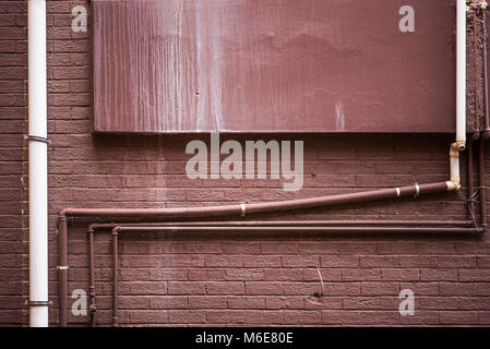 Grungy brown painted wall with pipes Stock Photo