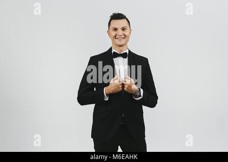 Attractive dark haired young man in tuxedo and bow tie, isolated at white background. Stock Photo