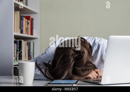 Tired girl resting her head on the table of working with computer Stock Photo
