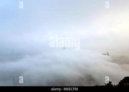 The foggy Hong Kong skyline. Many buildings are covered when viewed from the Peak. Only the tallest skyscrapers can have their upper part visible. Stock Photo