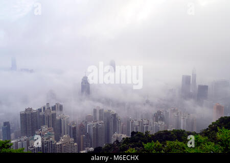 The foggy Hong Kong skyline. Many buildings are covered when viewed from the Peak. Only the tallest skyscrapers can have their upper part visible. Stock Photo