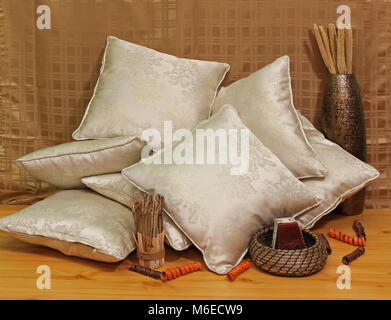Pile of silk beige pillows on brown background Stock Photo