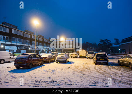 Cars parked in a car park which is covered in snow at night. Stock Photo