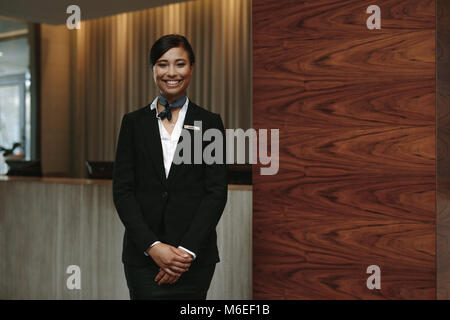 Portrait of happy female hotel receptionist standing at workplace. Smiling woman receptionist working in hotel. Stock Photo