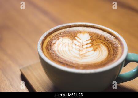 Close up hot cappuccino coffee cup with heart shape latte art on wood table at cafe,Drak tone filter,food and drink Stock Photo