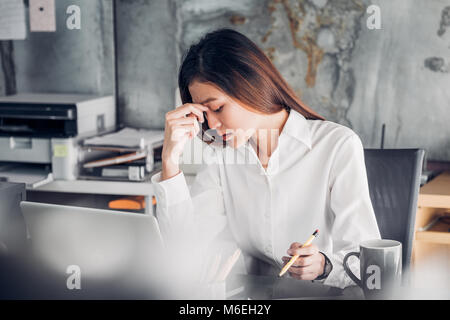 Frustrated Asian businesswoman cover her face with two hand and feel upset from work in front of laptop computer on desk at office,Stress office lifes Stock Photo