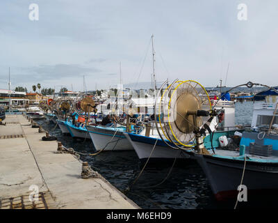 Fishing boats moored in old fishing harbour Kato Pafos Lower Pafos Paphos South Cyprus fisherman mending nets on his boat in popular tourist area Stock Photo