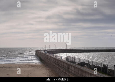 People walk on the habour wall road as the tide comes in on a sunny day in  Ramsgate, Kent Stock Photo
