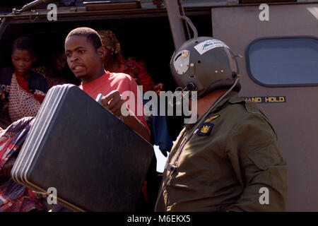 Floods in Mozambique, March 2000; Rescued people run to safety after a South African helicopter drops them on high ground  near Chibuto, Gaza Province. Stock Photo