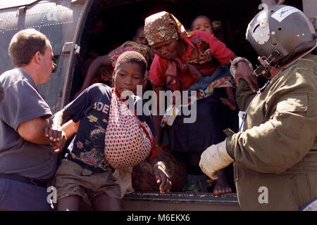 Floods in Mozambique, March 2000; Rescued people run to safety after a South African helicopter drops them on high ground  near Chibuto, Gaza Province. Stock Photo