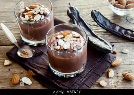 Chocolate (Carob) Mousse topped with Almond in glasses over wooden background close up - delicious homemade Raw Vegan Chocolate Pudding with Nuts and  Stock Photo