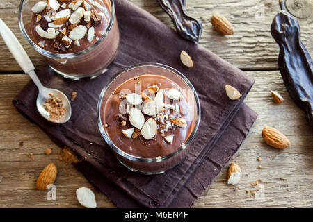 Chocolate (Carob) Mousse topped with Almond in glasses over wooden background close up - delicious homemade Raw Vegan Chocolate Pudding with Nuts and  Stock Photo
