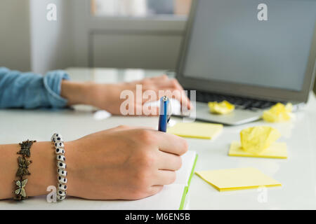 Female hands writing ideas on paper and working with laptop computer Stock Photo