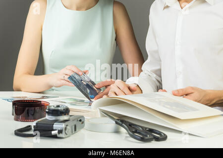 Young married or engaged couple puts analog printed pictures into wedding family photoalbum Stock Photo