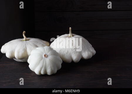 Three white patissons lie on an oak table. Copy space for your text. Stock Photo