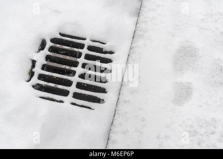 Snow covered kerbside / road drainage grid during the 2018 Beast from the East polar vortex snows which caused widespread problems for commuters. Stock Photo