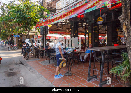 Senior woman reading menu outside Banana Leaf restaurant, Pub Street, Siem Reap, Cambodia Stock Photo