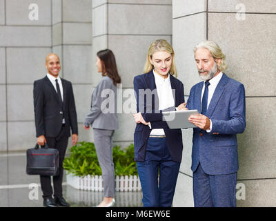 multinational corporate people standing talking in lobby of modern office building Stock Photo