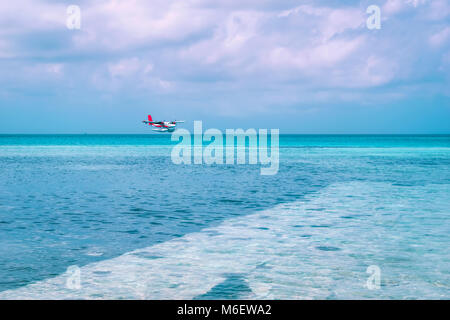 Seaplane laneding in sea at Maldives beach resort for holiday background Stock Photo